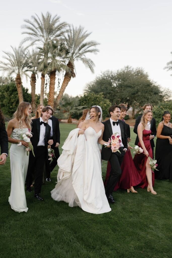 Wedding party laughing and walking together across the lawn, a high energy moment before the ceremony.