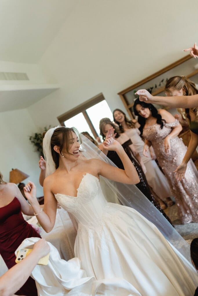 Bride dancing and laughing with her bridesmaids while getting ready.