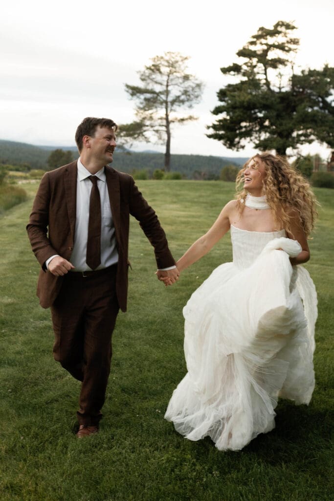 Bride and groom laughing together while holding hands in the meadow, Sunriver Resort wedding portrait, Central Oregon