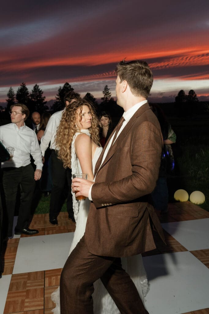 Bride and groom slow dancing together under a dramatic sunset sky, Sunriver Resort wedding, Central Oregon.