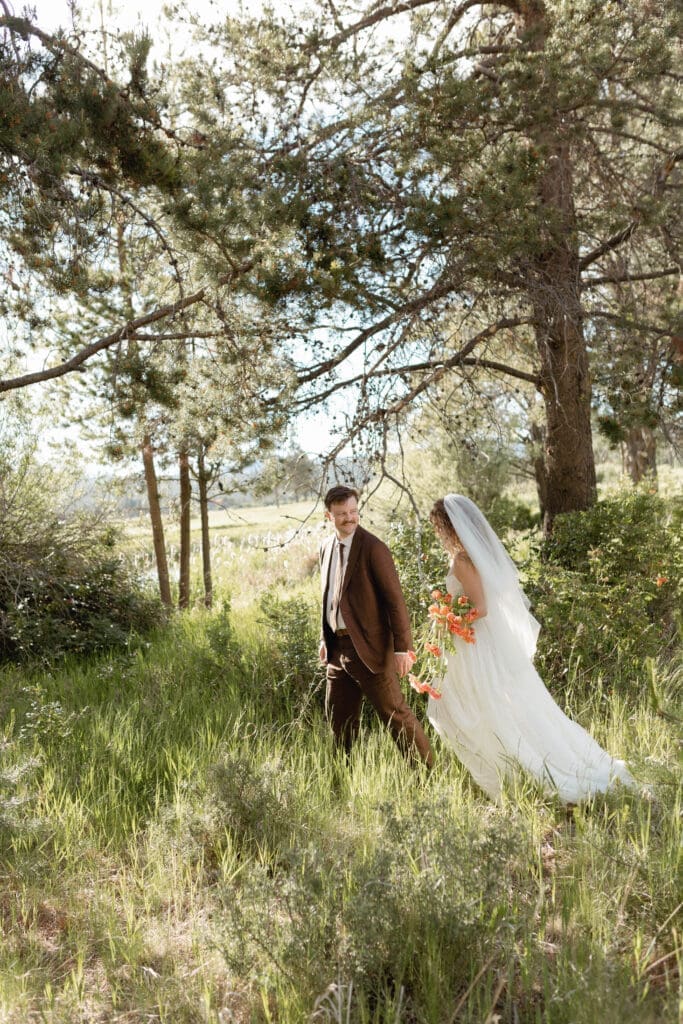 Bride and groom walking together through the pine trees for wedding portraits.
