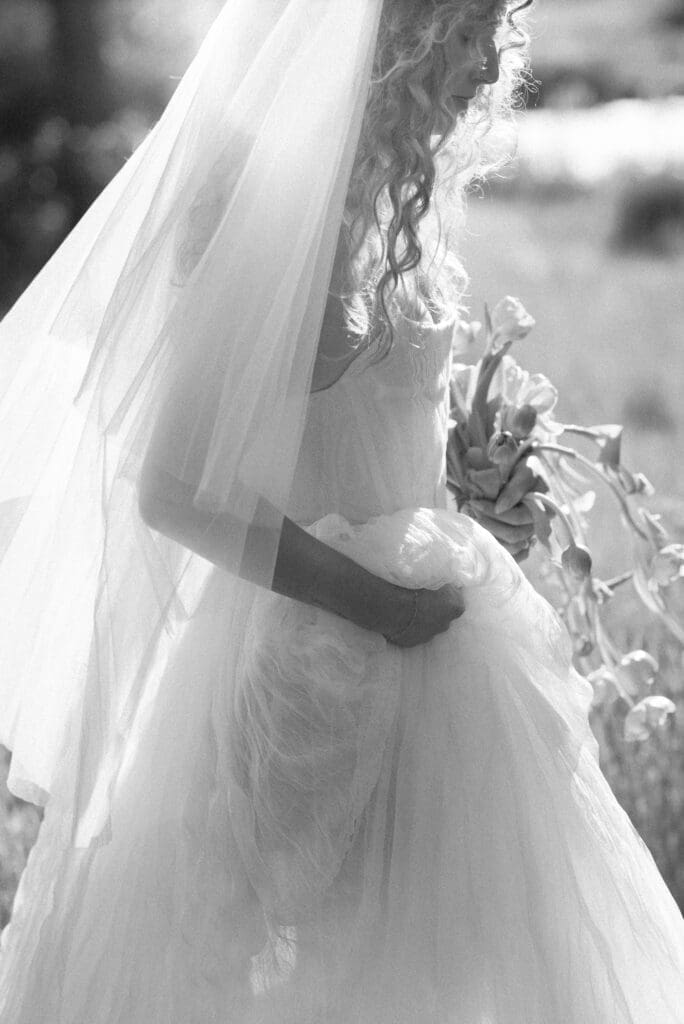 Black and white detail of the bride's veil and bouquet caught in motion