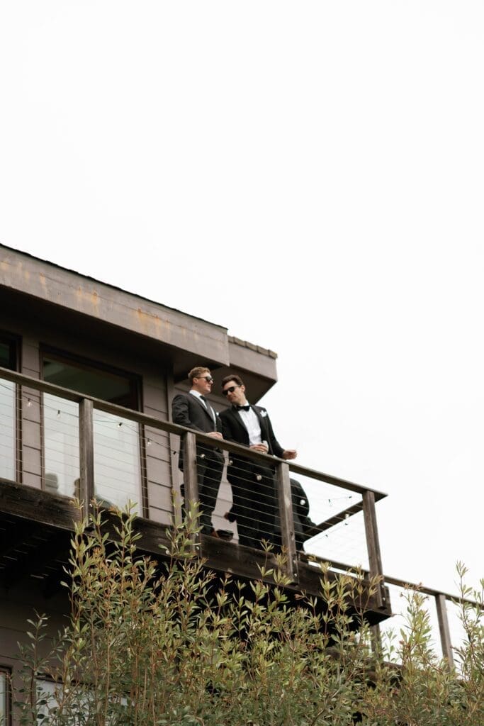 Guests in suits standing on a wooden deck under an overcast Big Sur sky.